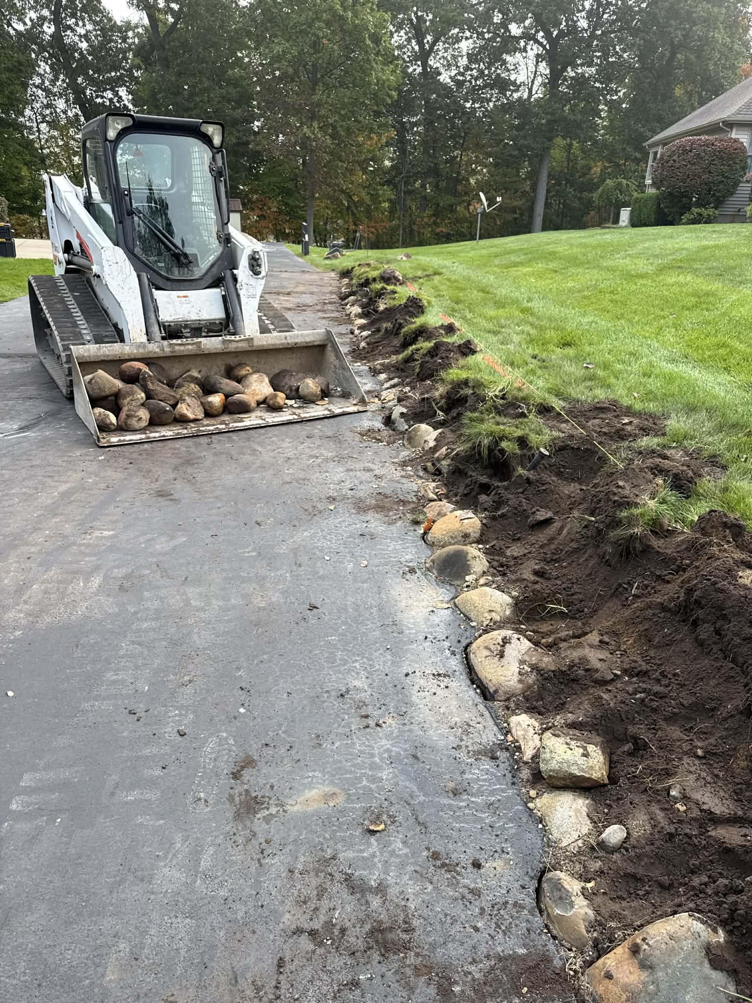 Bobcat removing stone during retaining wall site preparation