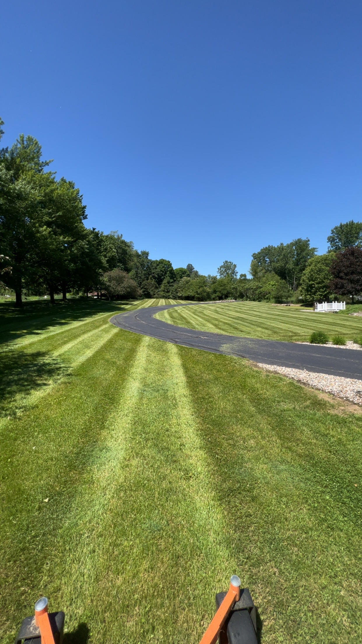 Large freshly mowed lawn with stripes following a curved driveway