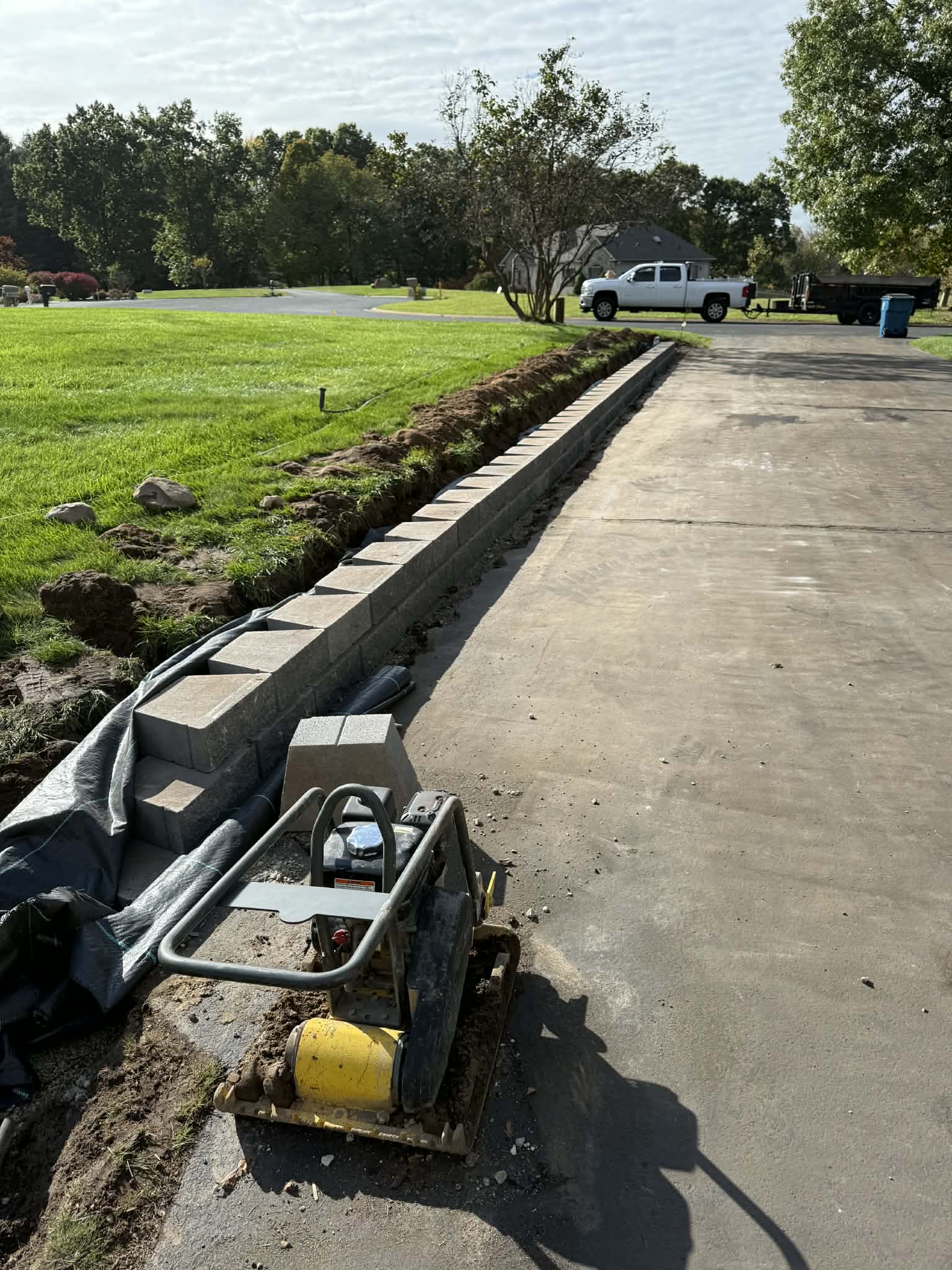 Retaining wall installation in progress along a driveway